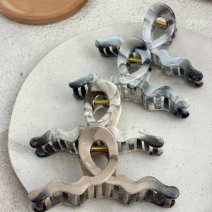 Vintage marble pattern wavy hair claw clips made of acetate displayed on a ceramic plate