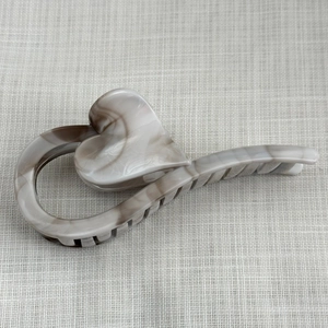 Detailed macro view of large heart-shaped hair claw clip with grey marble ink pattern texture