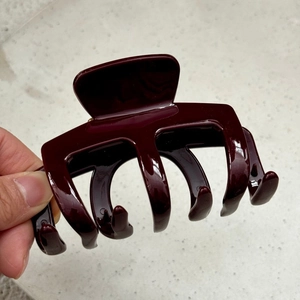 Close-up of a large burgundy shark hair claw clip with a glossy finish and metal spring