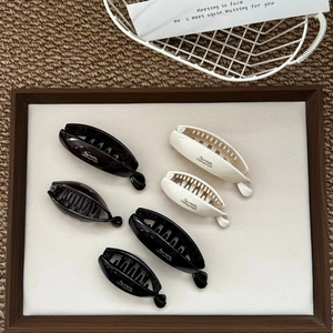 Detailed macro view of premium resin banana hair clips in black, brown and cream white