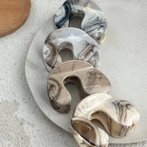 Close-up of four marble texture acetate hair claws in various neutral earthy colors