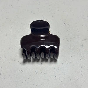Detail view of glossy dark brown hair claw clip with strong metal spring and smooth finish