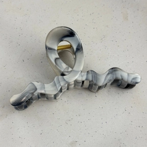 Detail view of large wave hair claw with fluid marble texture and gold metal spring