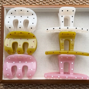 Polka dot hair claw clips set in cream, olive, and pink colors on a wooden tray