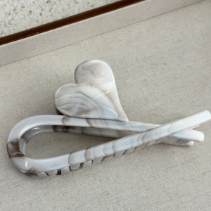 Detailed view of large marble texture heart hair claw clip on soft fabric background