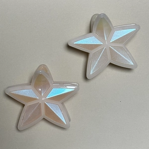 Macro shot of two star-shaped hair claws with pearlescent finish and geometric faceted surface