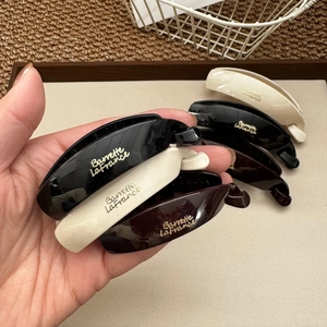 Three minimalist French-style banana hair clips in black, white, and brown colors