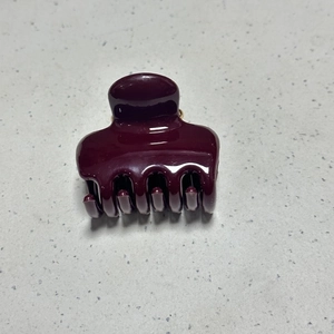 Detail view of large burgundy hair claw clip with glossy finish and spring mechanism