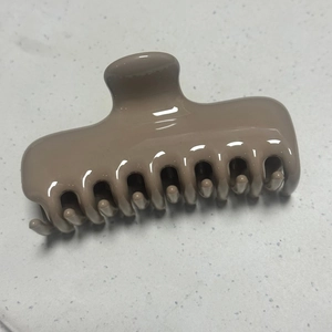 Glossy light brown rectangular hair claw clip detail on a white marble surface
