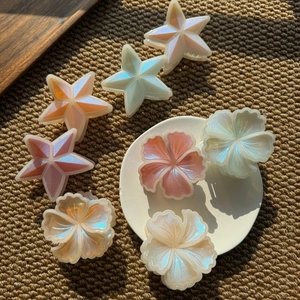 Détails de pinces à cheveux en forme d'étoile et de fleur avec un fini nacré sur un tapis
