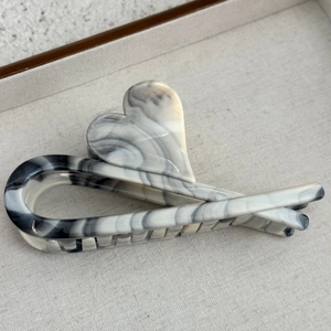 Detailed macro view of heart-shaped hair claw clip with black and white marble resin texture