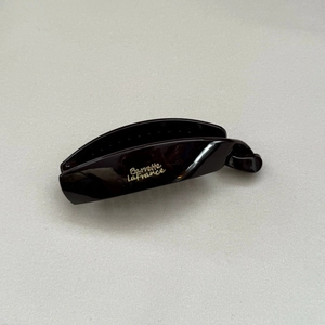 Macro shot of dark glossy banana clip with Barrette LaFrance gold lettering detail