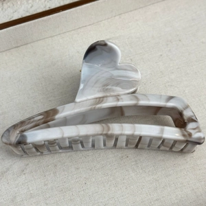 Detail of large marble pattern hair claw clip with heart shape and secure grip teeth