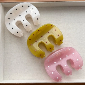 Three elegant polka dot hair claws in white, green, and pink colors on display