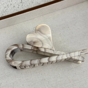 Macro view of marbled cream acetate hair claw clip with interlocking heart detail