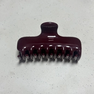 Close-up of a glossy dark burgundy hair claw clip with dense teeth and smooth finish