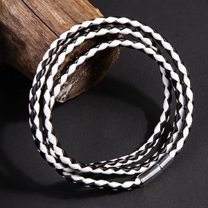 Dettaglio del bracciale multistrato in pelle intrecciata bianca e nera con chiusura magnetica