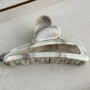 Detailed view of large marble pattern hair claw with 3D heart on textured background