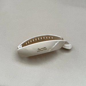Close-up of cream white banana hair clip with gold lettering and inner teeth detail