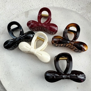 Bow hair claw clips set in black, wine red, and cream on a grey stone display plate