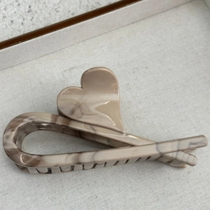 Macro detail of elegant marble patterned heart hair claw clip with smooth glossy finish
