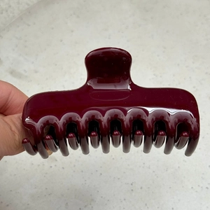 Close-up of the burgundy hair claw clip with glossy finish and dense spring-loaded teeth