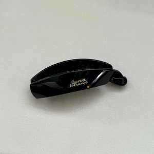 Detail view of the polished black banana hair clip with elegant gold Barrette lettering