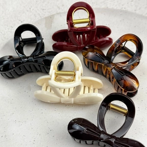 Five assorted colors of elegant bow hair clips displayed on a white stone tray