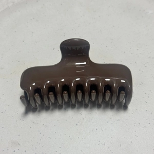 Detailed top view of a glossy dark brown hair claw clip with a strong spring and curved teeth