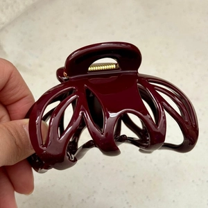 Macro detail of a large burgundy hair claw clip with golden spring and glossy finish