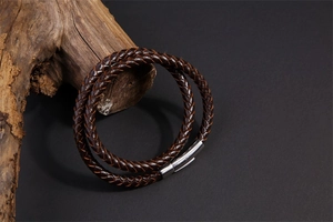 Detailed macro view of dark brown braided leather bracelet with silver matte metal clasp