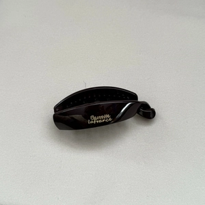 Close-up of a glossy dark brown banana hair clip with golden Barrette La France text