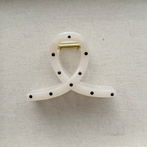 Detailed close-up of cream polka dot hair claw with a durable gold metal spring