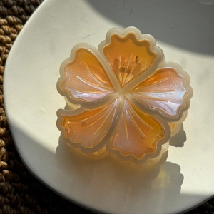 Détail d'une pince à cheveux fleur orange nacrée en résine avec des pétales brillants