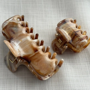Detailed close-up of large and small amber tortoiseshell hair claws with glossy finish