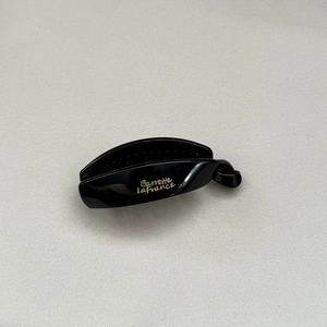 Detail view of black glossy acrylic banana clip with gold Barrette LaFrance text