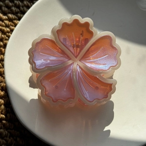 Détail de la pince à cheveux hibiscus corail avec finition nacrée et dorée
