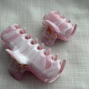 Detail view of ink marble hair claw set with pink and white swirl patterns and metal spring