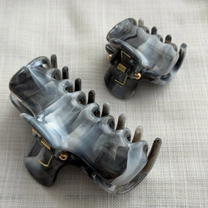 Detail view of large and small marble pattern hair claws with gold springs on fabric