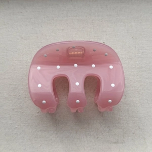 Detailed view of pink translucent polka dot hair claw clip with golden metal spring