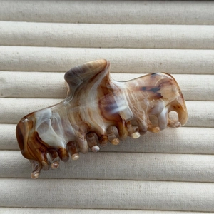 Detailed macro of the marbled acetate hair claw clip with brown and beige texture