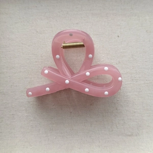 Detailed top view of a pink polka dot hair claw clip with a strong golden metal spring