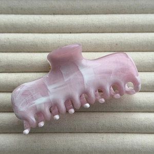Detail view of pink and white marble ink texture on a large resin hair claw clip