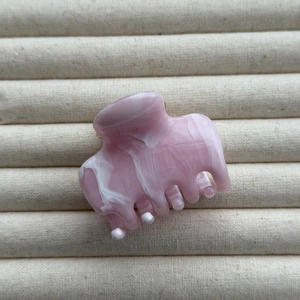 Macro detail of ink-wash marble pattern on a pink and white hair claw clip closeup
