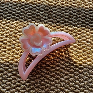 Detail showing pink floral hair claw clip with pearlescent resin petals on a textured surface