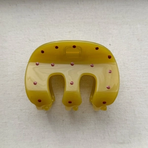 Detailed view of an olive green hair claw clip with red polka dots and metal spring