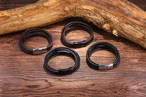 Detail of multi-layer braided leather bracelets with magnetic clasps on a rustic wood base