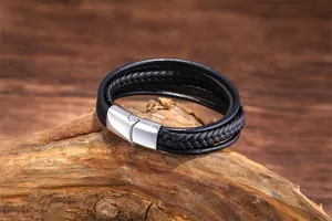 Detail of multi-layer braided black leather bracelet with silver magnetic clasp on wood