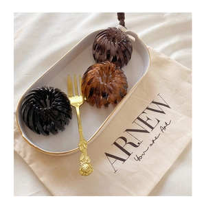 Three bird nest hair clips in black, coffee, and amber on a decorative tray
