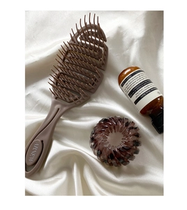 Close-up of bird nest hair claw clip and professional styling brush on silk fabric